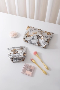 Flat lay of satin butterfly cosmetic bags with makeup brushes and an eyeshadow palette
