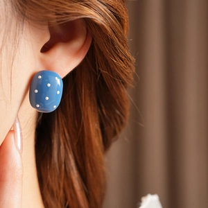 Dettaglio orecchini ovali blu a pois indossati dalla modella per uno stile retrò