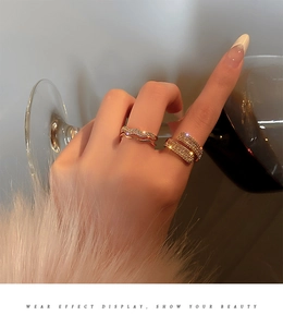 Detailed view of gold plated sparkling rhinestone rings set on a hand holding a wine glass