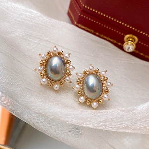 Macro view of vintage oval blue pearl stud earrings with white pearl border on silk