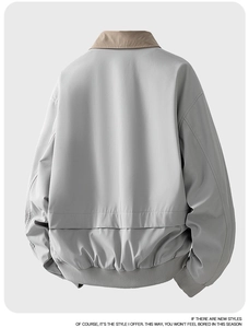 Dettaglio del bomber color-block con polsini a costine e colletto kaki su tessuto grigio chiaro