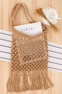 Flat lay of a beige handmade crochet beach bag with tassels on a rustic wooden background