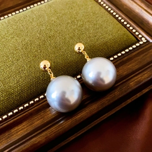 Detailed view of vintage gold plated earrings with large grey pearls on a retro background