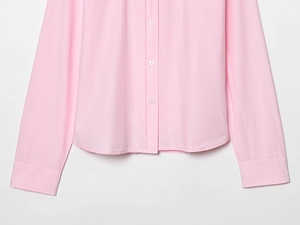 Detailed view of pink poplin shirt hem, button placket, and fine cotton fabric texture