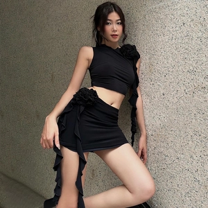 Close-up of black two-piece set featuring 3D floral accents and ruffled edge details