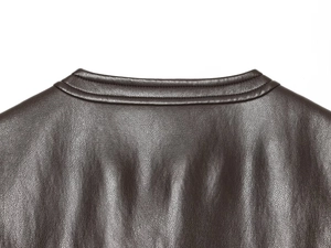 Detail of dark brown leather vest collar showing texture and fine stitching lines