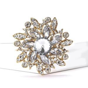 Macro detail of luxury gold flower brooch with sparkling rhinestones on white background