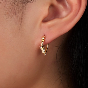 Close-up of golden S925 silver hoop earrings with pave cubic zirconia on female ear