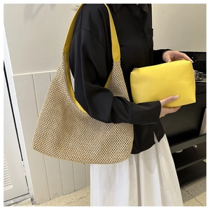 Detail of woven straw tote bag and yellow PU cosmetic pouch set held by a model