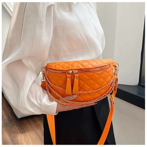 Detail of orange quilted crossbody bag with triple metal chains and adjustable strap