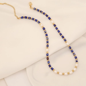 Vue détaillée des perles de pierre bleue et des perles blanches sur le collier doré