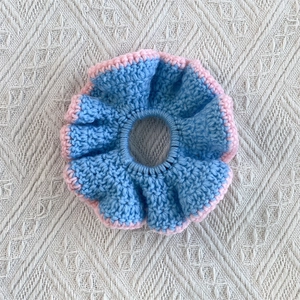 Detail of handmade crochet ruffle hair tie in pastel blue and pink knit material