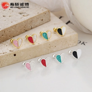 Detail view of heart-shaped screw back earrings in gold and silver finish with enamel