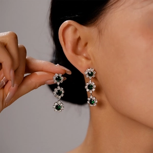 Close-up of three-tier flower earrings with green crystal and sparkling rhinestones