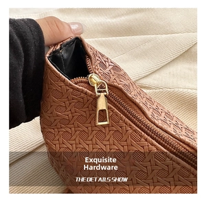 Close-up of brown woven leather handbag with premium gold metal zipper details