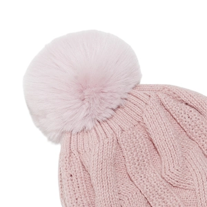 Close-up of pink cable knit beanie featuring a fluffy faux fur pom-pom detail