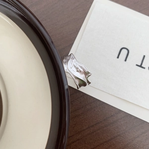 Detailed view of silver ring with irregular lava texture placed on a ceramic plate edge