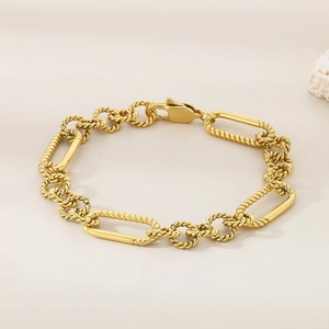 Close-up of golden mixed link chain bracelet with lobster clasp on beige surface