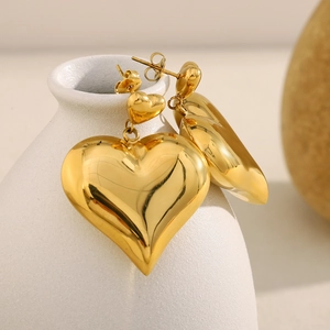 Detail of 18K gold plated double heart hollow stud earrings on white ceramic