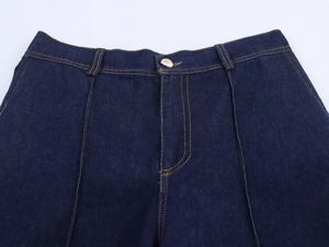 Detail einer dunkelblauen Jeans mit Fokus auf Taillenverschluss und goldenem Knopf