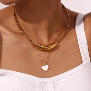 Detailopname van gelaagde 18K gouden ketting met hartjeshanger en schelpletter C accent