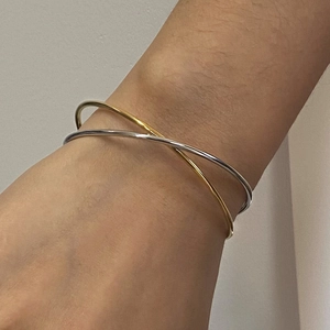 Detail shot of two-tone gold and silver crossover stainless steel bracelet on wrist