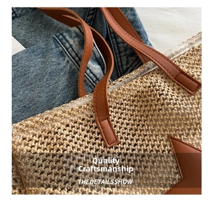 Close-up of woven straw tote bag with brown leather handles and star patch detail
