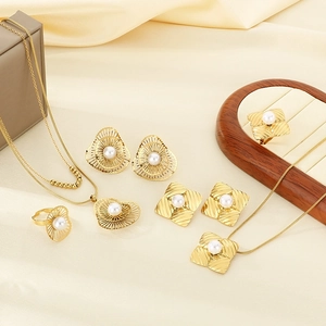 Detailed flat lay of gold stainless steel jewelry set with hollow flower patterns and pearls