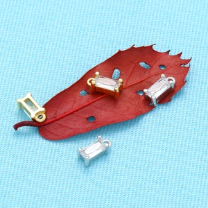 Vue détaillée de pendentifs rectangles en zircon or et argent sur feuilles rouges