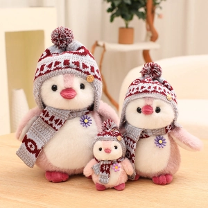 Three sizes of cute pink plush penguins with knitted hats and scarves on wood table