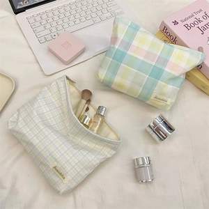 Close-up of checkered fabric makeup bags with organized skincare products and brushes