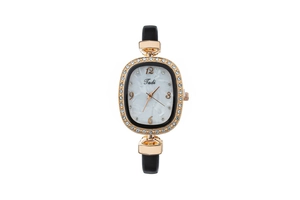 Détail d'une montre ovale or rose avec lunette strass et cadran en marbre blanc