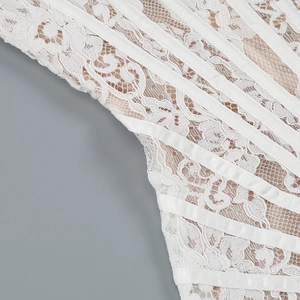 Detailed close-up of white lace fabric with satin boning structure on a corset dress