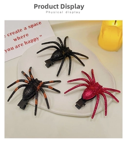 Three glittery spider hair clips for Halloween in black and orange on a white tray