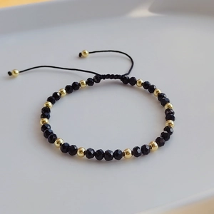 Detail of adjustable beaded bracelet with black crystals and gold-tone polished beads