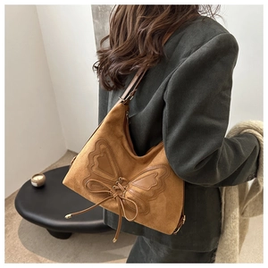 Detailed view of brown suede shoulder bag featuring a large decorative butterfly and drawstring