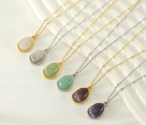Close-up of teardrop stone pendants on thin gold and silver stainless steel chains