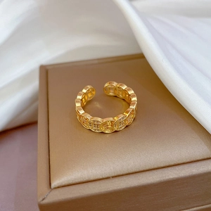 Adjustable gold open ring with hollow copper coin pattern on champagne jewelry box