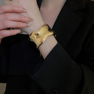 Macro view of wide irregular wave-shaped gold cuff bracelet with mirror finish on model