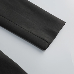 Close-up of black twill fabric texture and fine stitching on the blazer dress sleeve