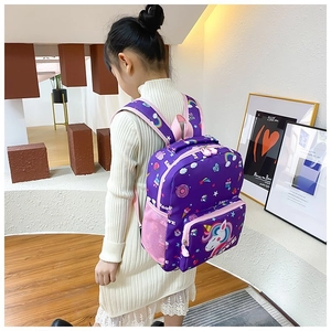 Girl wearing a purple unicorn backpack with rainbows and donuts in a home setting
