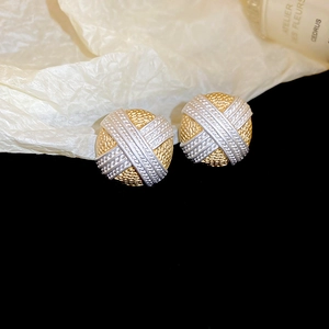 Dettaglio macro di orecchini a bottone tondi bicolore con trama intrecciata oro e argento