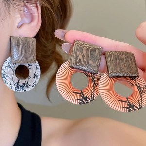 Detail of geometric wood and resin drop earrings with Chinese calligraphy and bamboo art
