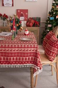 Close-up of red Christmas tablecloth with white fringe edges and festive elk pattern