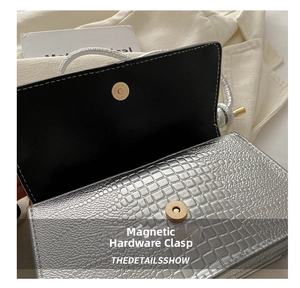 Détail du sac argenté à motif crocodile montrant le bouton pression magnétique doré