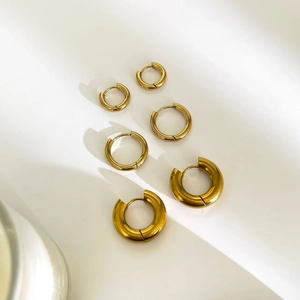 Three pairs of polished gold titanium steel hoop earrings in varied sizes for women