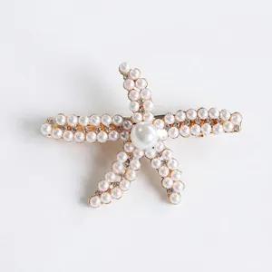 Gold starfish hair clip with faux pearls and rhinestones on a white background