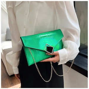 Dettaglio della pochette a busta verde motivo serpente con catena dorata e fibbia