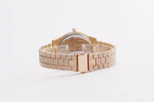 Detail of rose gold ladies watch featuring rhinestone encrusted metal band and folding clasp