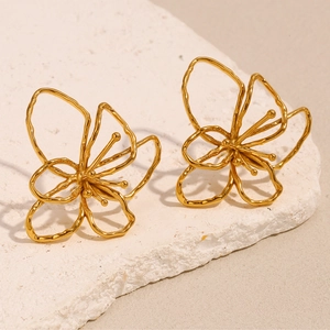 Dettaglio di orecchini a fiore traforato placcati in oro 18K su pietra bianca